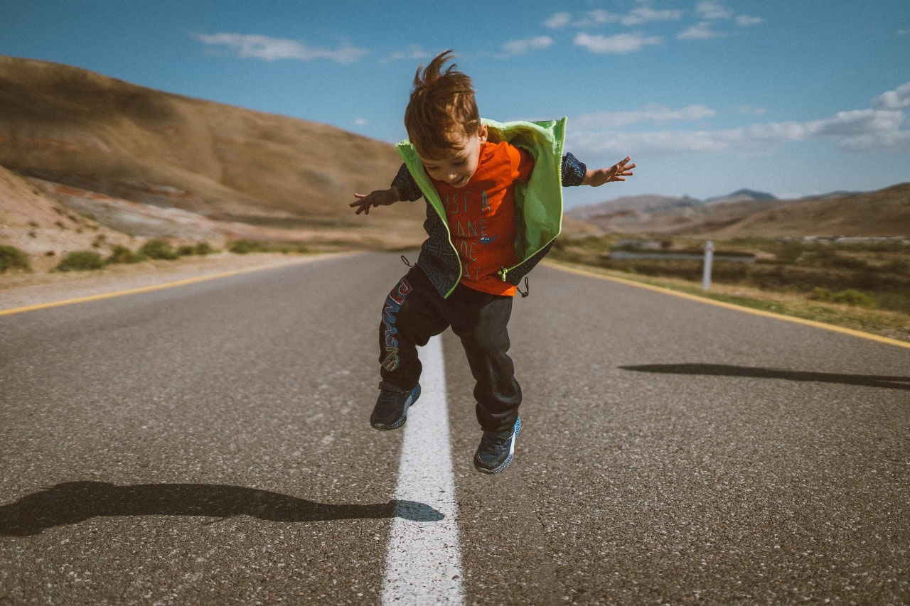 child jumping on a highway road