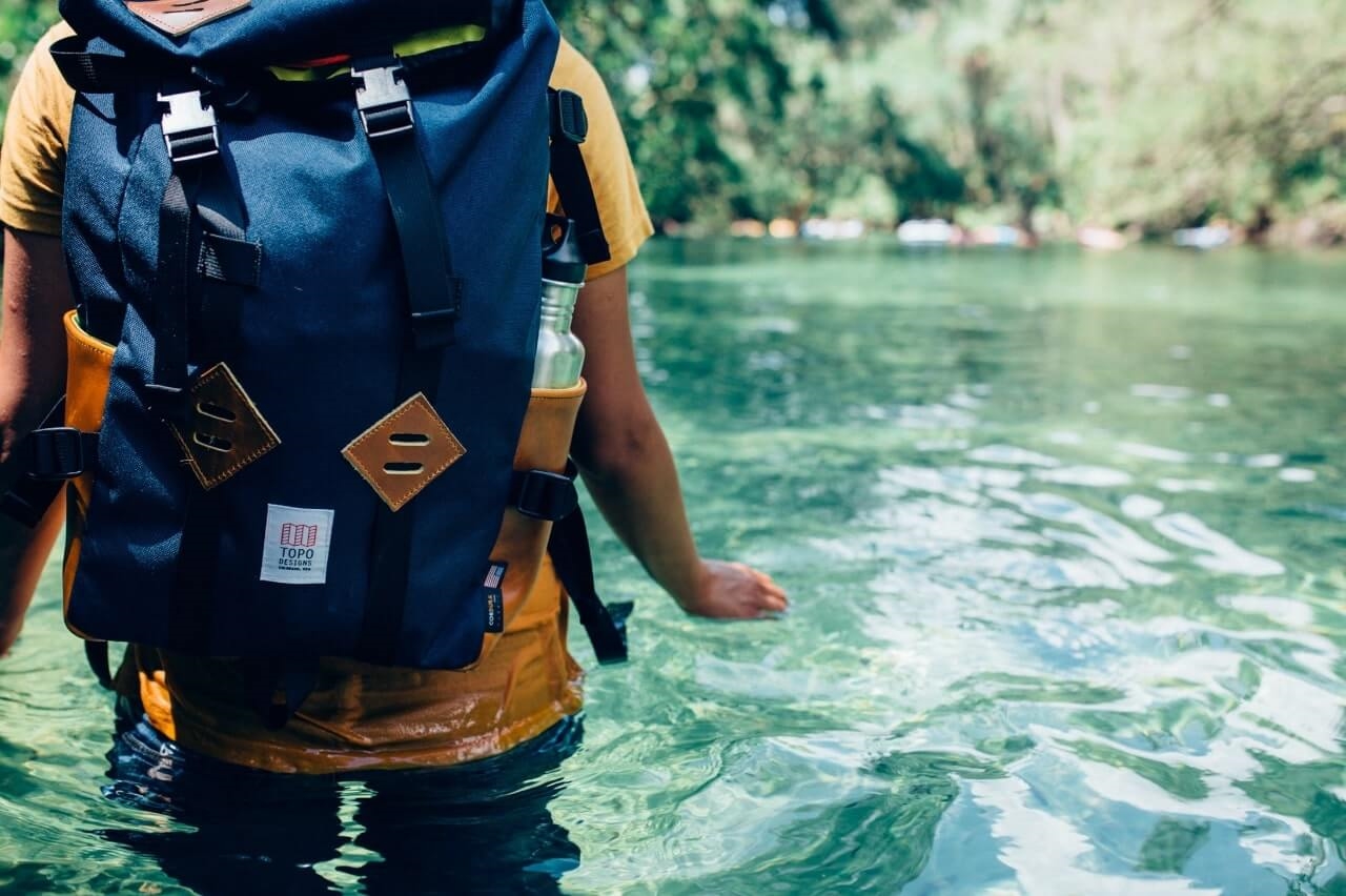Walking through water with a packed hiking bag